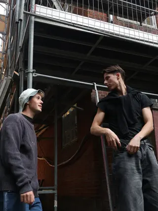 The duo talking outside beside scaffolding
