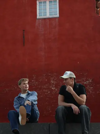 Sitting together beside a red wall